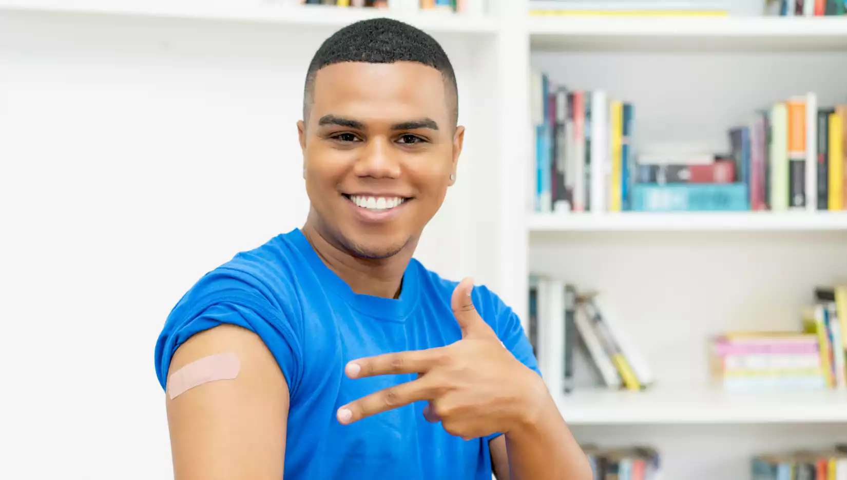Handsome African American young adult man with plaster after vaccination against Covid 19