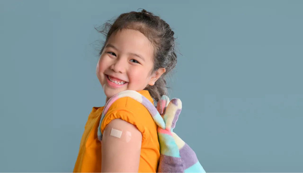 Coronavirus Vaccination Advertisement. Happy Vaccinated Little asian girl Showing Arm With Plaster Bandage After Covid-19 Vaccine Injection , Smiling To Camera. New normal back to school concept