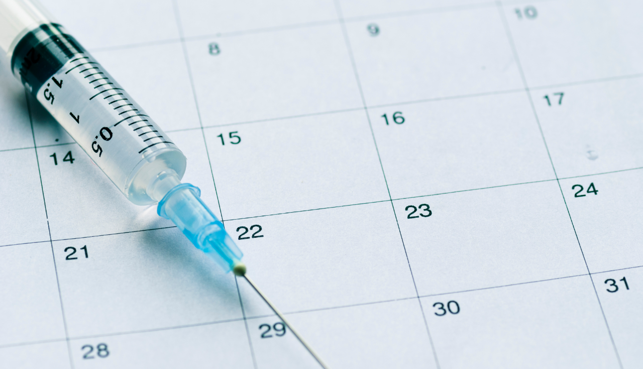 Medical syringe on calendar background