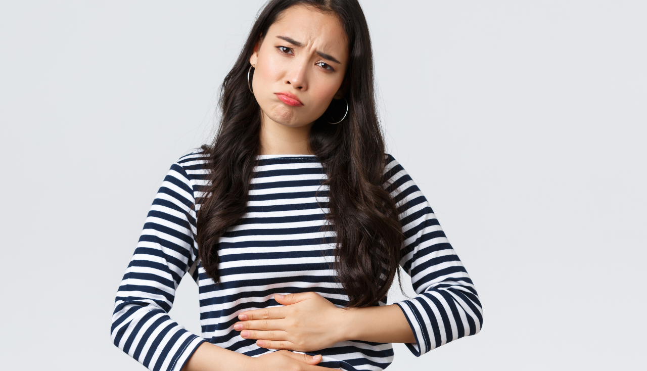 Lifestyle, beauty and fashion, people emotions concept. Woman got food poisoned, touching belly feeling unwell. Asian girl with cramps looking gloomy, having menstrual pain, white background