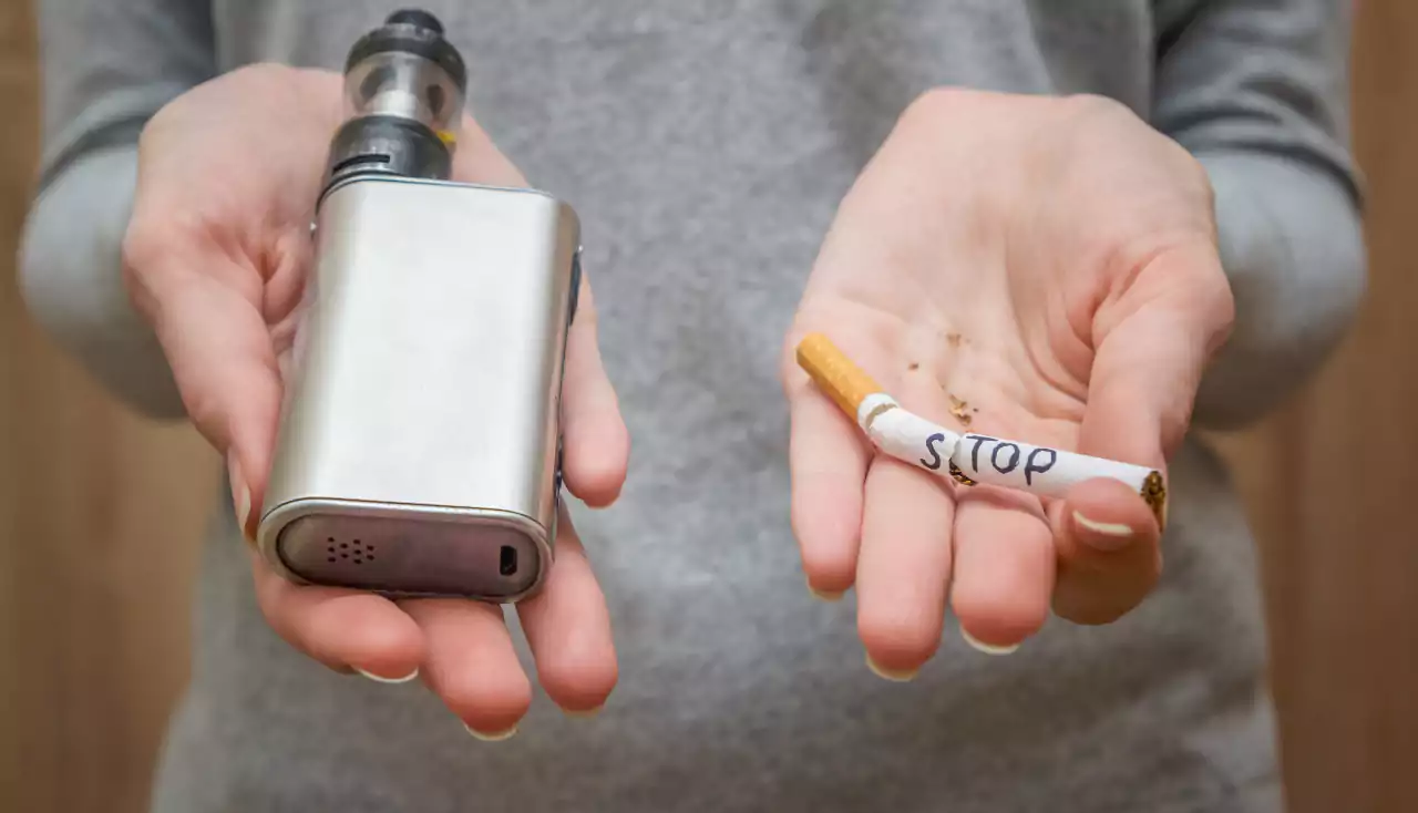 girl holds on her palms vape and a broken cigarette with the word stop, close-up
