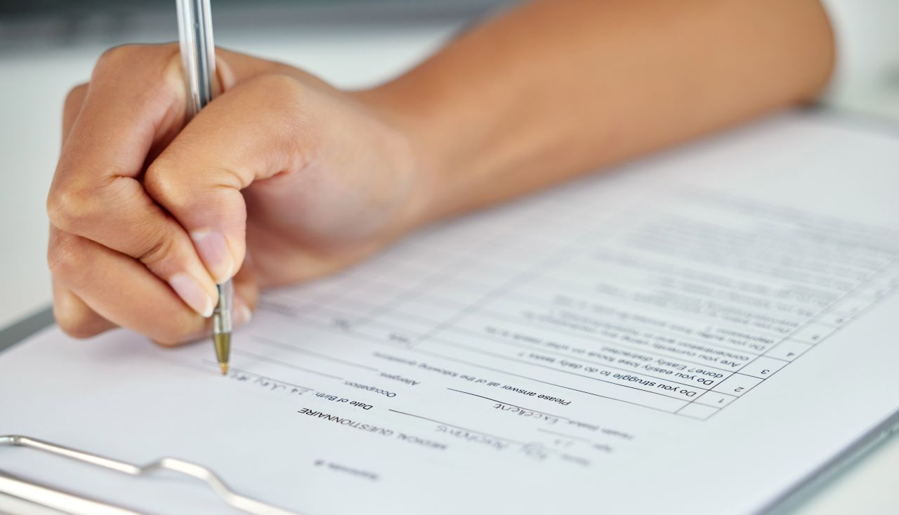 person completing a form with a pen