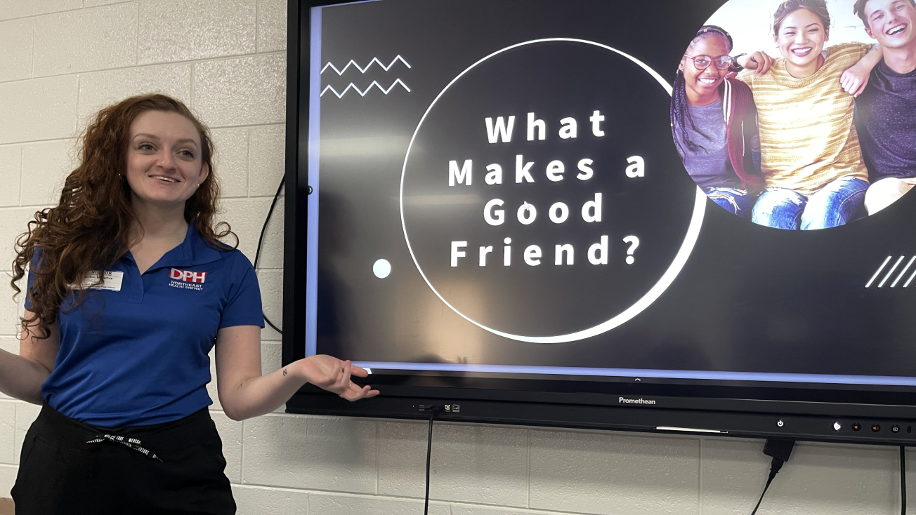 Image of a health educator presenting about What Makes a Good Friend on a screen behind her.